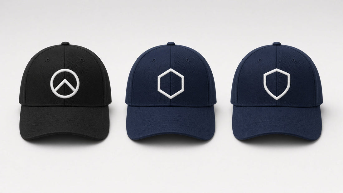 Flat lay of embroidered black and navy baseball caps on a light grey surface