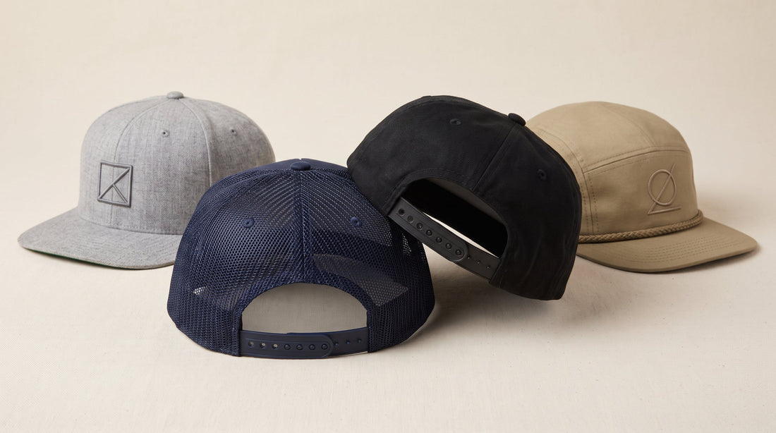 Four custom snapback caps with the plastic snap closure straps visible, including a mesh back trucker snapback and a five panel rope cap