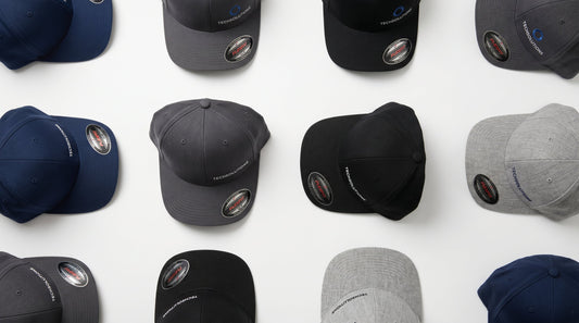 Professional flat lay of wholesale Flexfit stretch-fit baseball caps in navy, black, and grey on a clean white surface