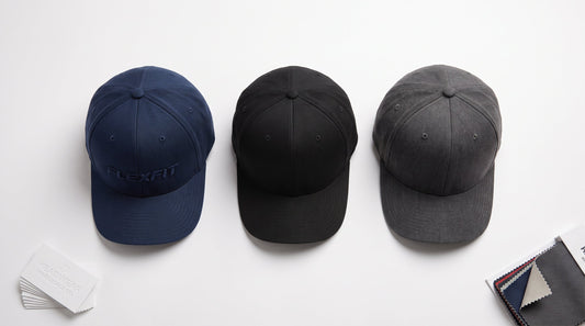 Wholesale Flexfit hats flat lay — structured baseball caps in navy, black and charcoal for embroidery programs