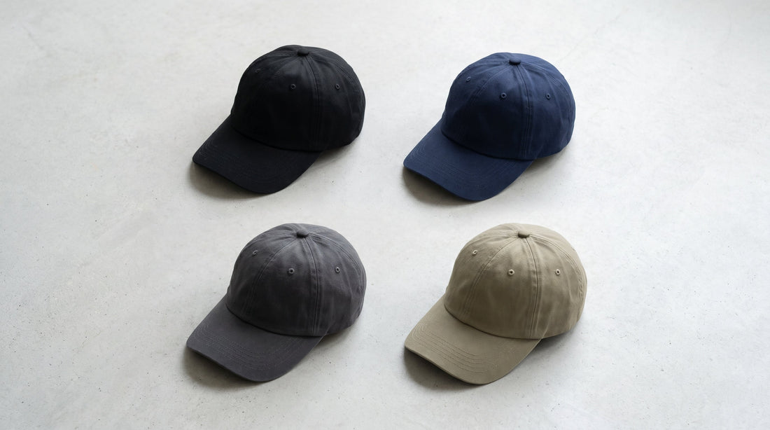 Blank dad hats in black, navy, charcoal, and khaki arranged in a flat lay