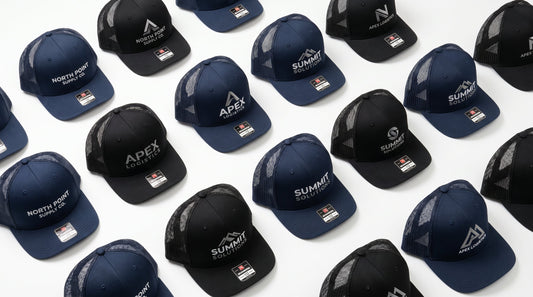 Custom embroidered trucker hats in navy and black arranged in a flat lay product photography style