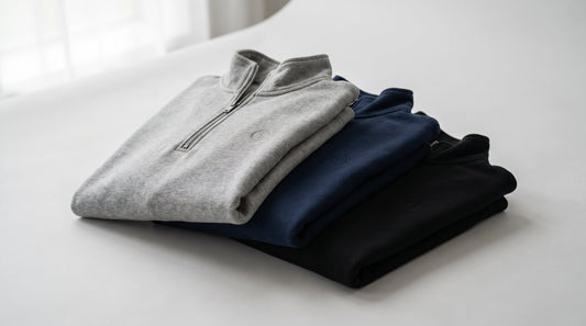 Embroidered quarter zip pullovers in navy, heather grey, and black folded and stacked for a company logo program