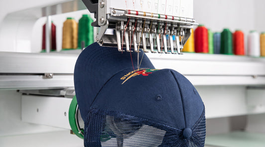 Navy trucker cap being custom embroidered on a commercial embroidery machine